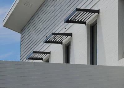 Black metal window awnings on a white building exterior.