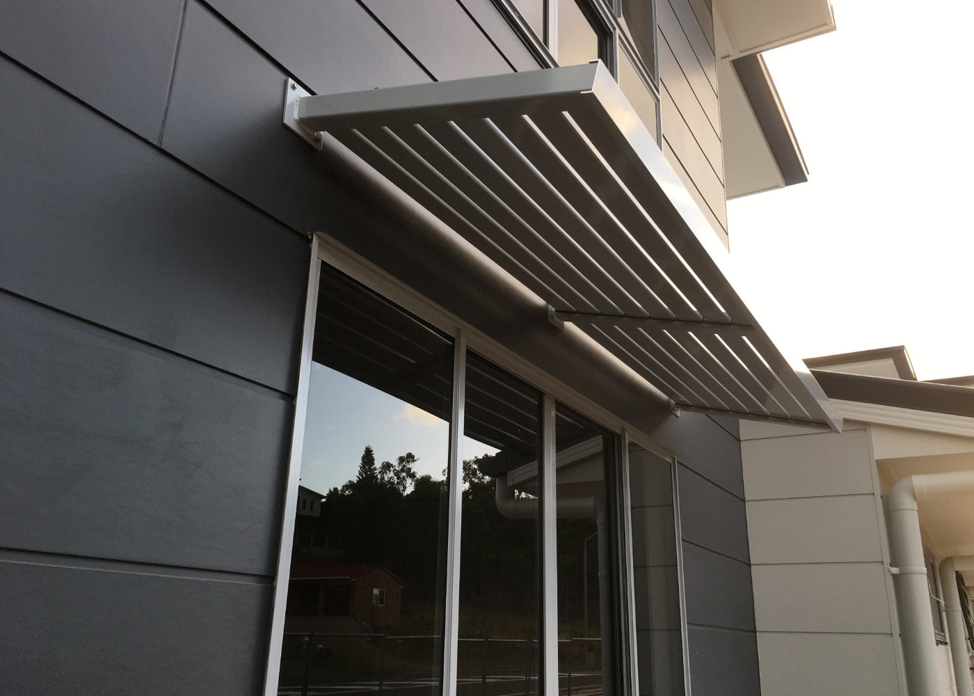 Aluminium Slat Awning from the Clik'n'Fit Collection in Dune on an angle above a large residential window.