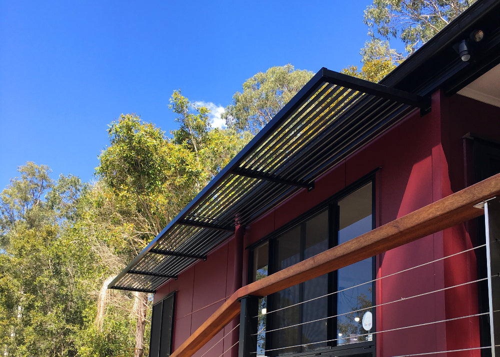 A black Aluminium Louvre Awning from the Clik'n'Fit Collection on dark red house in Australian Bush