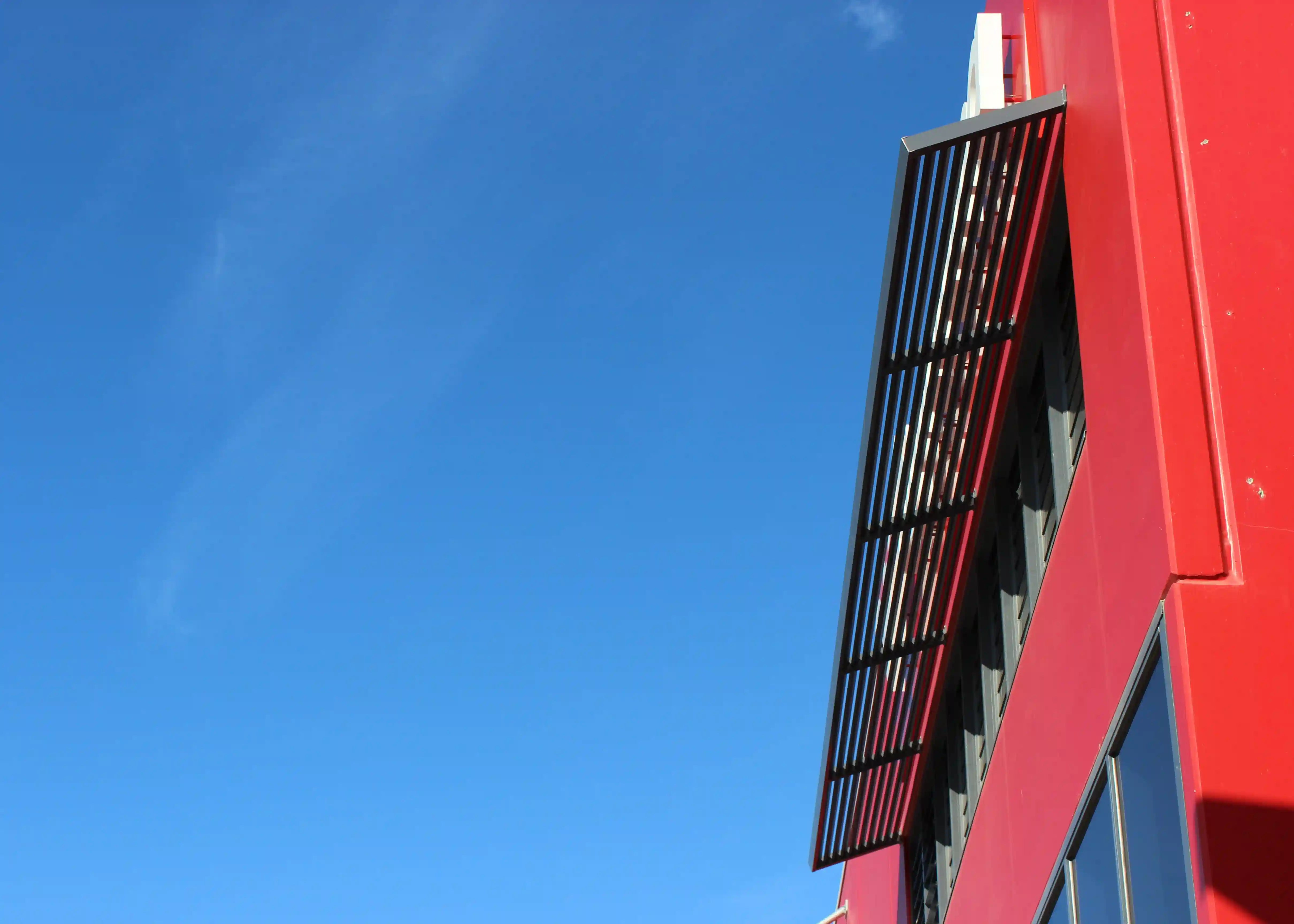 Aluminium Louvre Awning in  Woodland Grey  installed at an angle on bright red Factory.