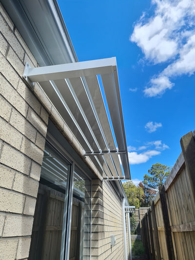 Pearl White Slat Awning with Centre Bracket on a brick house