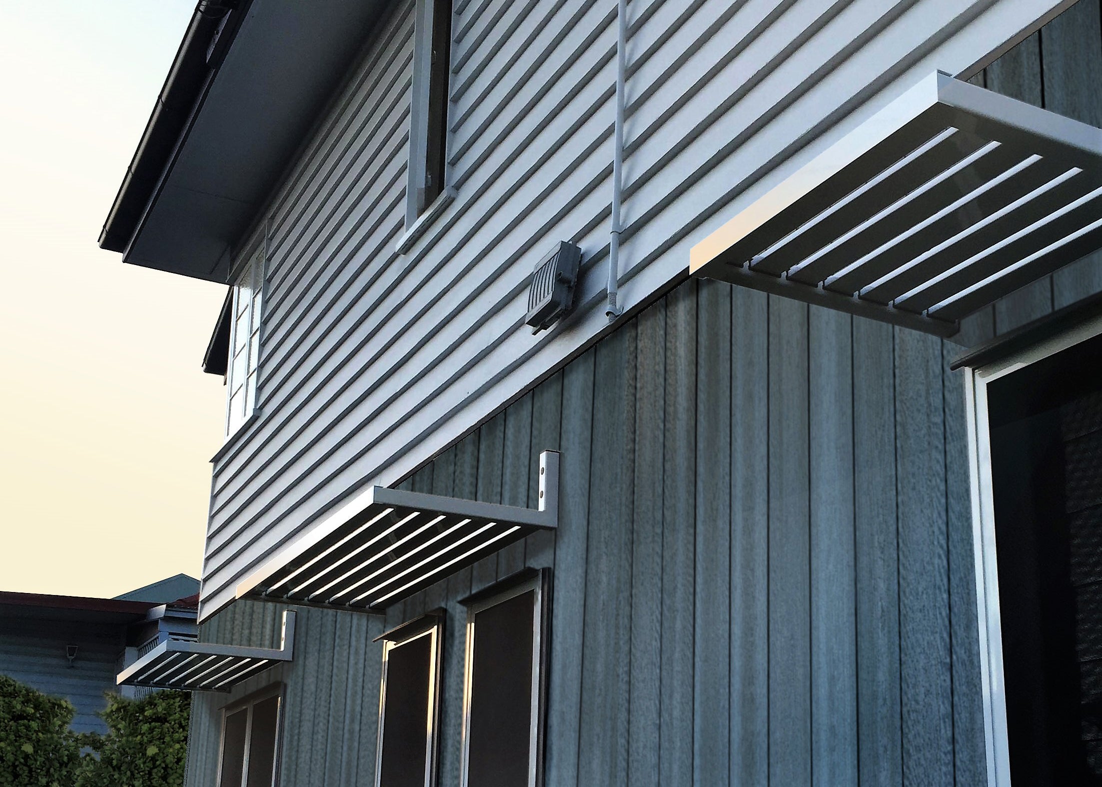 3x Clik'n'Fit® Aluminium Slat Awning in Ironstone on house above windows.